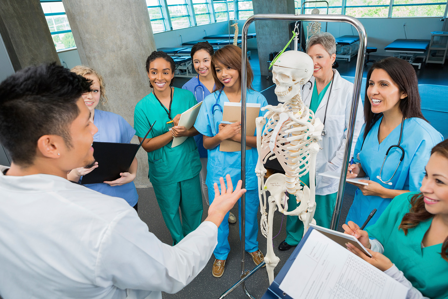 Medical school professor with a group of medical students showing a model human skeleton